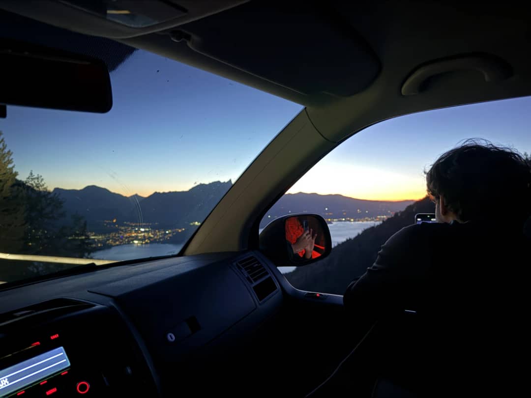 Afterglow over Lake Thun seen from a car parked at a Beatenberg viewpoint, the lights of the lakeside towns below