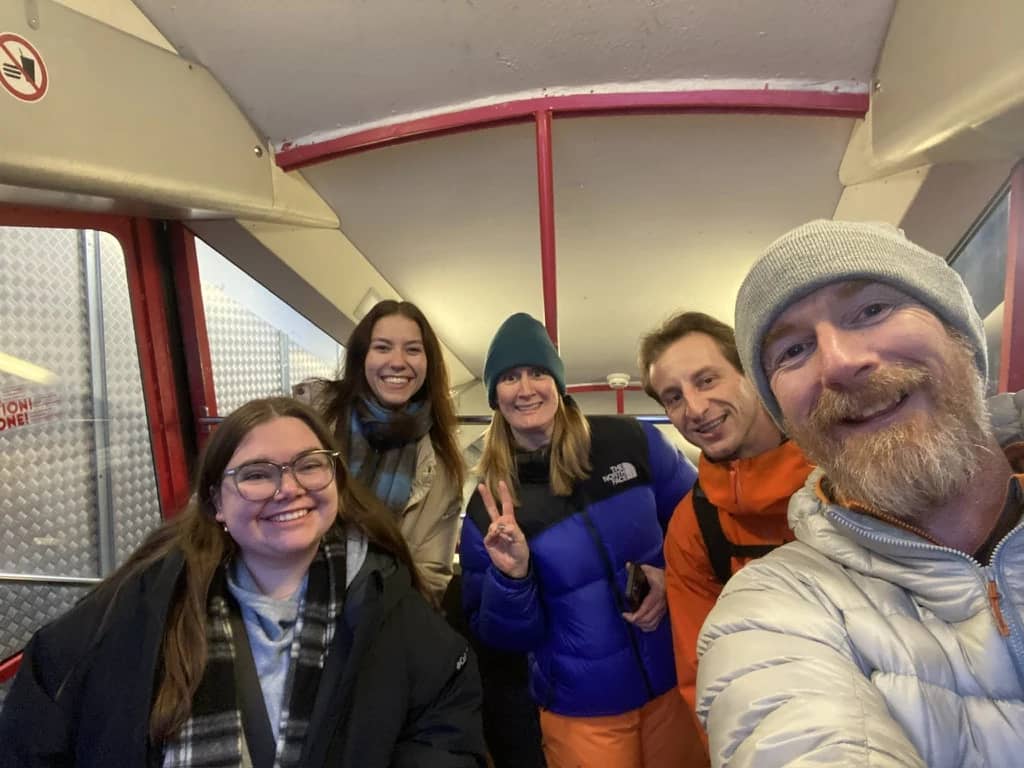 Grupo sonriente con chaquetas de invierno en una cabina roja del tren de montaña de Mürren, en enero