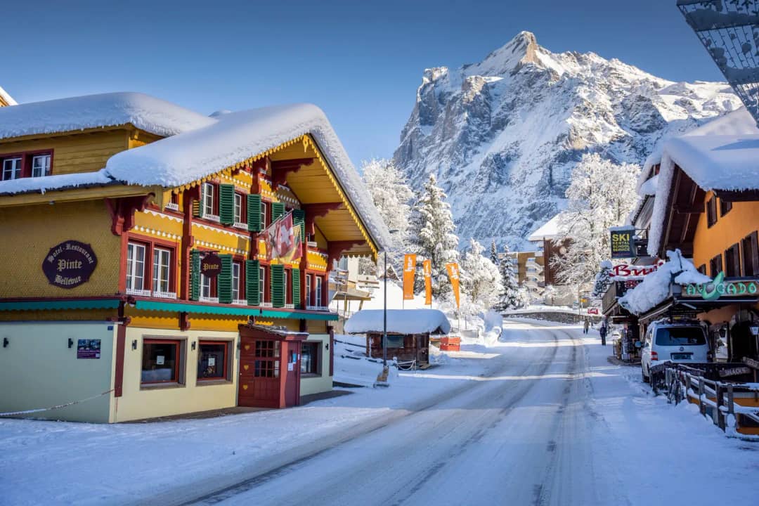 Chalés nevados y tiendas en la calle principal de Grindelwald bajo el Wetterhorn, un día soleado de invierno