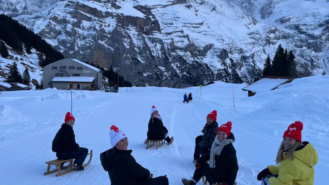 Seis huéspedes con trineos de madera en la pista de Mürren bajo la Jungfrau, una salida guiada al anochecer