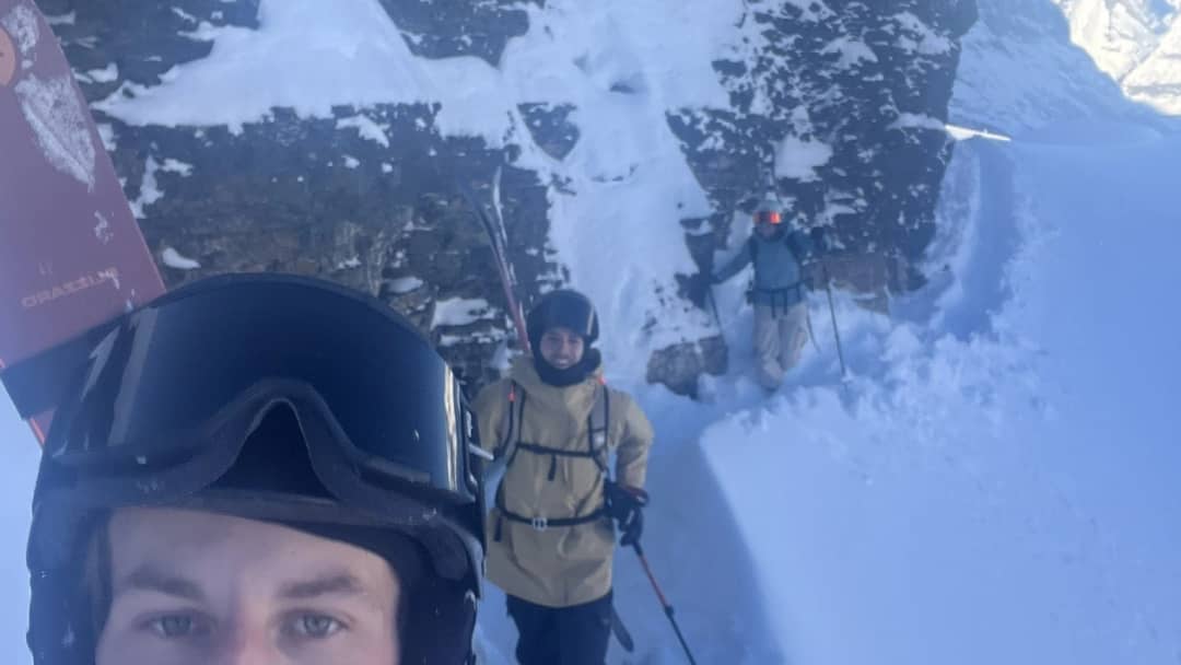 Pierre in roter Jacke mit zwei Freunden auf Ski in einem verschneiten Felscouloir unter dem Lauberhorn