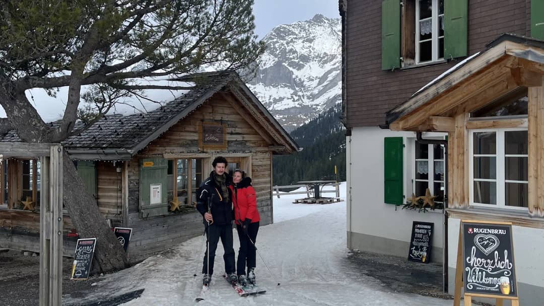 Zwei Skifahrer vor einem Berghaus auf der Männlichen-Seite des Skigebiets Grindelwald-Wengen, März